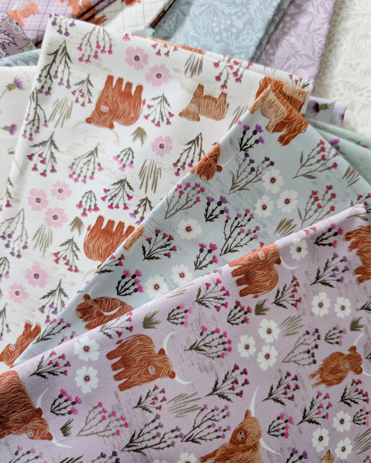 Summer Meadow Highland cut fabric from A Celtic Summer collection by Lewis & Irene features Highland cows and Scottish thistle in shades of Cream, Breezy Blue, and Light Heather.
