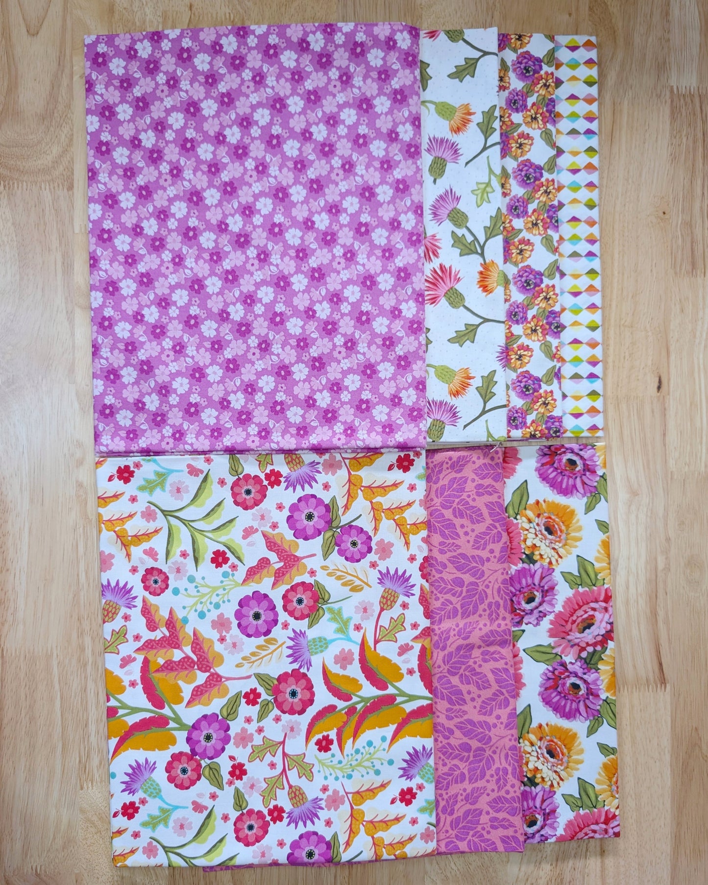 Seven fabrics showcasing brightly colored zinnias across white and pink backgrounds for vibrant floral quilting.