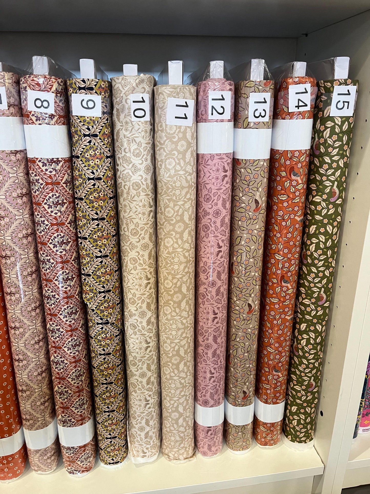 Bolts of arts and craft patterned fabric from the Isabella Collection by Lewis and Irene, labeled eight through fifteen.
