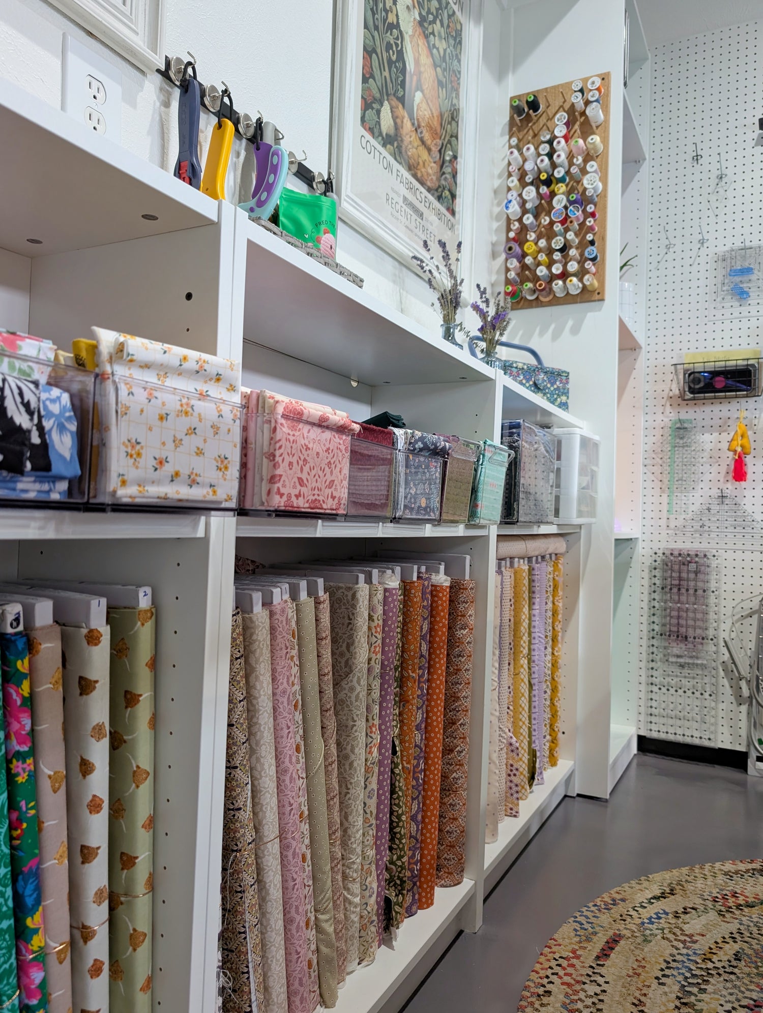 Rows of fabric bolts and cut fabrics line the shelves of the Sew Pretty Quilt Co studio, showcasing a modern yet charming collection of colors and patterns.